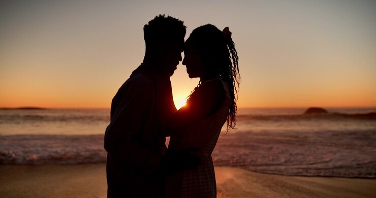 Jeune couple s'embrassant sur la plage au coucher du soleil