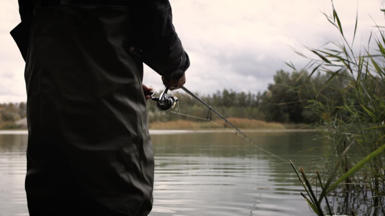 Tangan seorang pemancing dengan joran pancing di tangan, gerakan super lambat