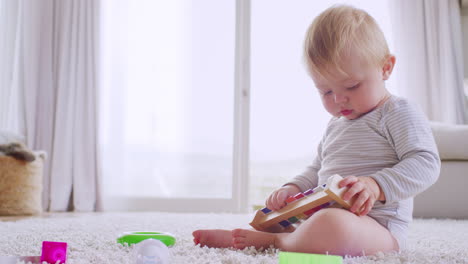 Toddler-sitting-on-floor-playing-with-xylophone,-close-up