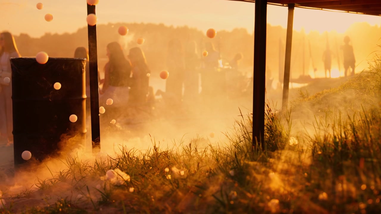Svævende bobler og røg ved strandfest i solnedgang