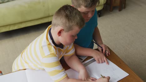 caucasian boy with his brother sitting at table and learning at home