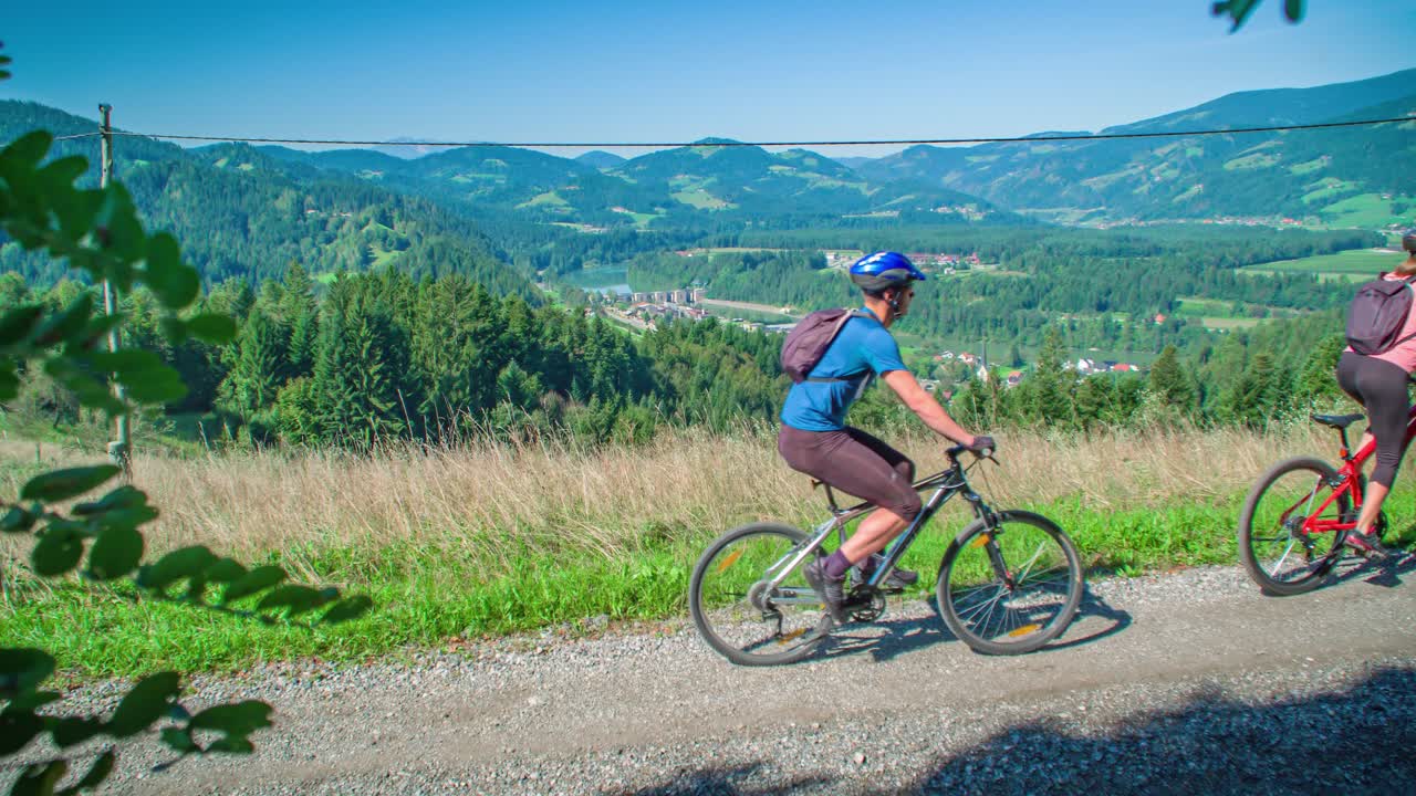 Two active couple ride bikes in tour around Vuzenica, Slovenia, slowmo