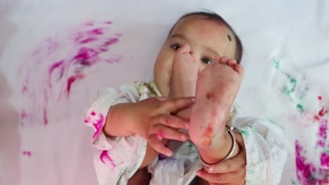 infant paying holi in traditional dress with colors from top angle