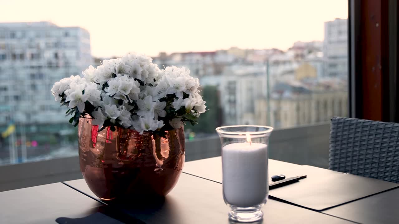 mesa de restaurante al aire libre con vista a la ciudad y flores