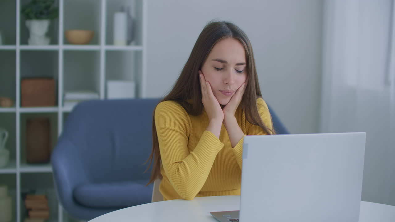 dolor de muelas. mujer molesta en el lugar de trabajo usa una computadora portátil tiene dolor de muelas y se toca la cara con la mano. concepto de enfermedad dental