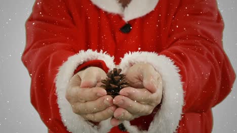 Video-composition-with-falling-snow-over-santa--holding-pine-cone-in-hands