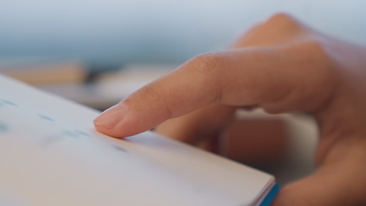 Finger tapping calendar dates on planner page in deliberate scheduling moment project manager marks deadline, parent books appointment, student checks exam date, index finger presses gently under soft