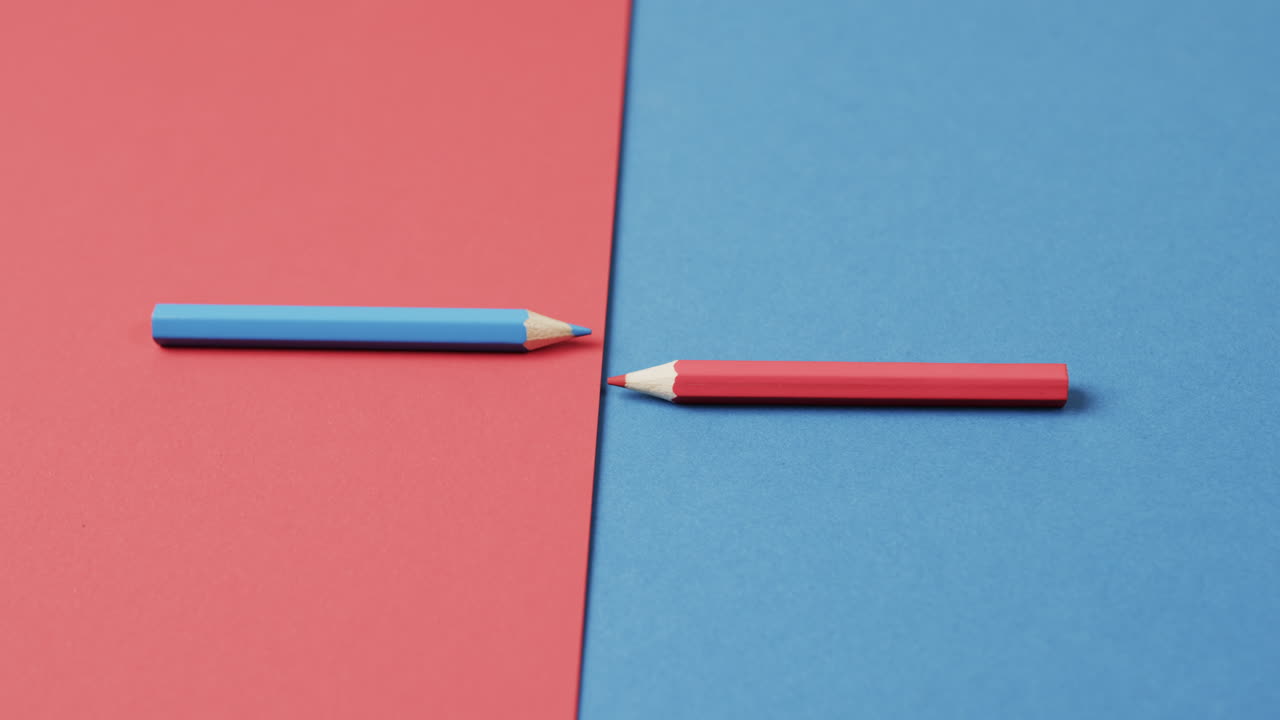 primer plano de lápices de colores azules y rojos dispuestos sobre un fondo rojo y azul, en cámara lenta