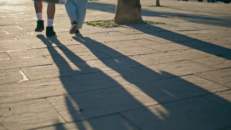 closeup pair shoes crossing sunny alley at city. romantic couple legs walking