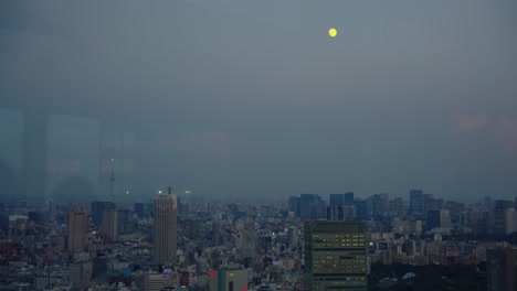 moon over tokyo japan as night falls over shinjuku urban suburb