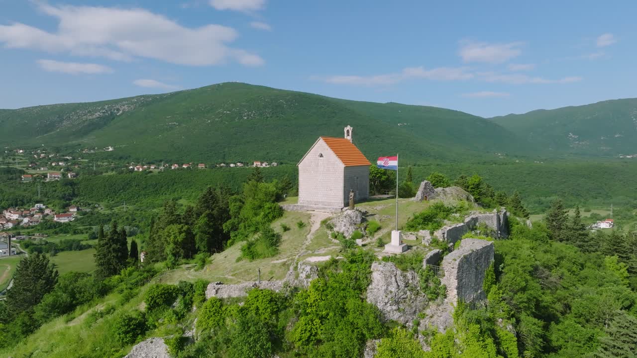 bandera croata y iglesia en la cima de una colina visitando la pintoresca ciudad de sinj en croacia