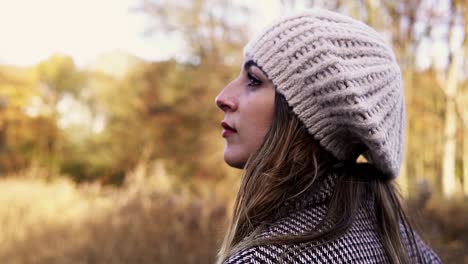 shot of a caucasian woman in an autumn dress walking and looking up in the middle of a park