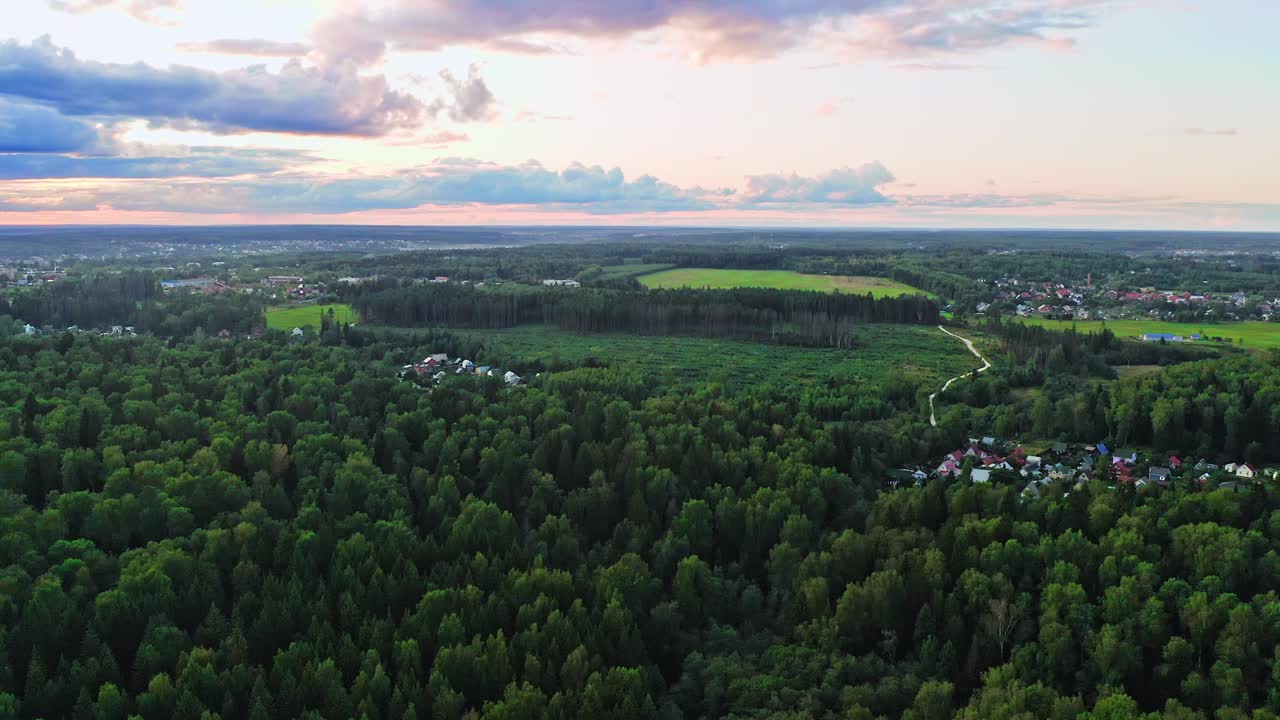 일몰 후 활엽수 숲과 작은 마을 위로 비행