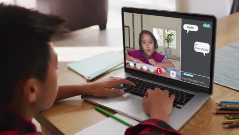 schoolboy using laptop for online lesson at home, with girl talking and web chat on screen