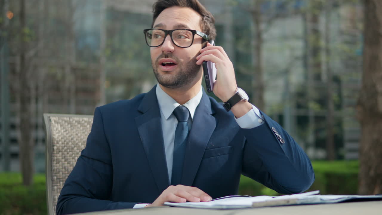 feliz emocionado hombre de negocios exitoso haciendo una llamada telefónica y hablando en el teléfono inteligente con su pareja sentado al aire libre en el parque compartiendo buenas noticias, celebrando logros, emociones positivas