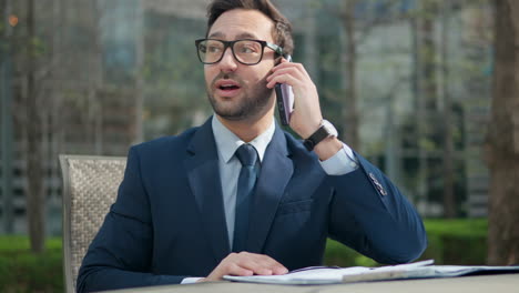 Feliz-Y-Exitoso-Hombre-De-Negocios-Haciendo-Llamadas-Telefónicas-Y-Hablando-Por-Teléfono-Inteligente-Con-Un-Compañero-Sentado-Al-Aire-Libre-En-El-Parque-Compartiendo-Buenas-Noticias,-Celebrando-Logros,-Emociones-Positivas