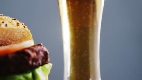 beer and hamburger against grey background