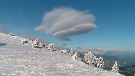 snowy mountain top with unusual clouds