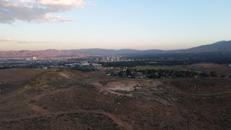 aerial shot revealing the skyline of reno, nevada from behind a hill in the nearby desert