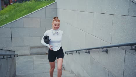 woman with yoga mat and water bottle on stairs