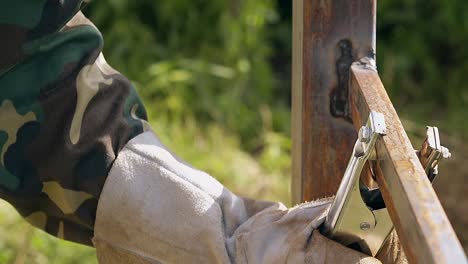 close-view-handyman-in-workwear-takes-away-clamp-from-fence