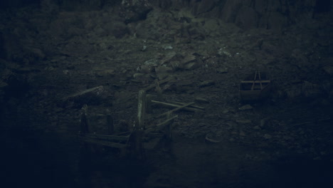 misty shoreline with remnants of boats at dusk near rocky cliffs