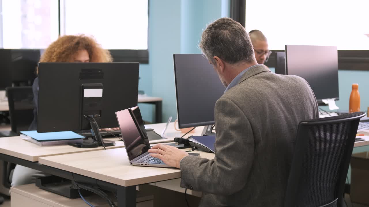 Manager analyzing documents and using laptop at coworking workspace