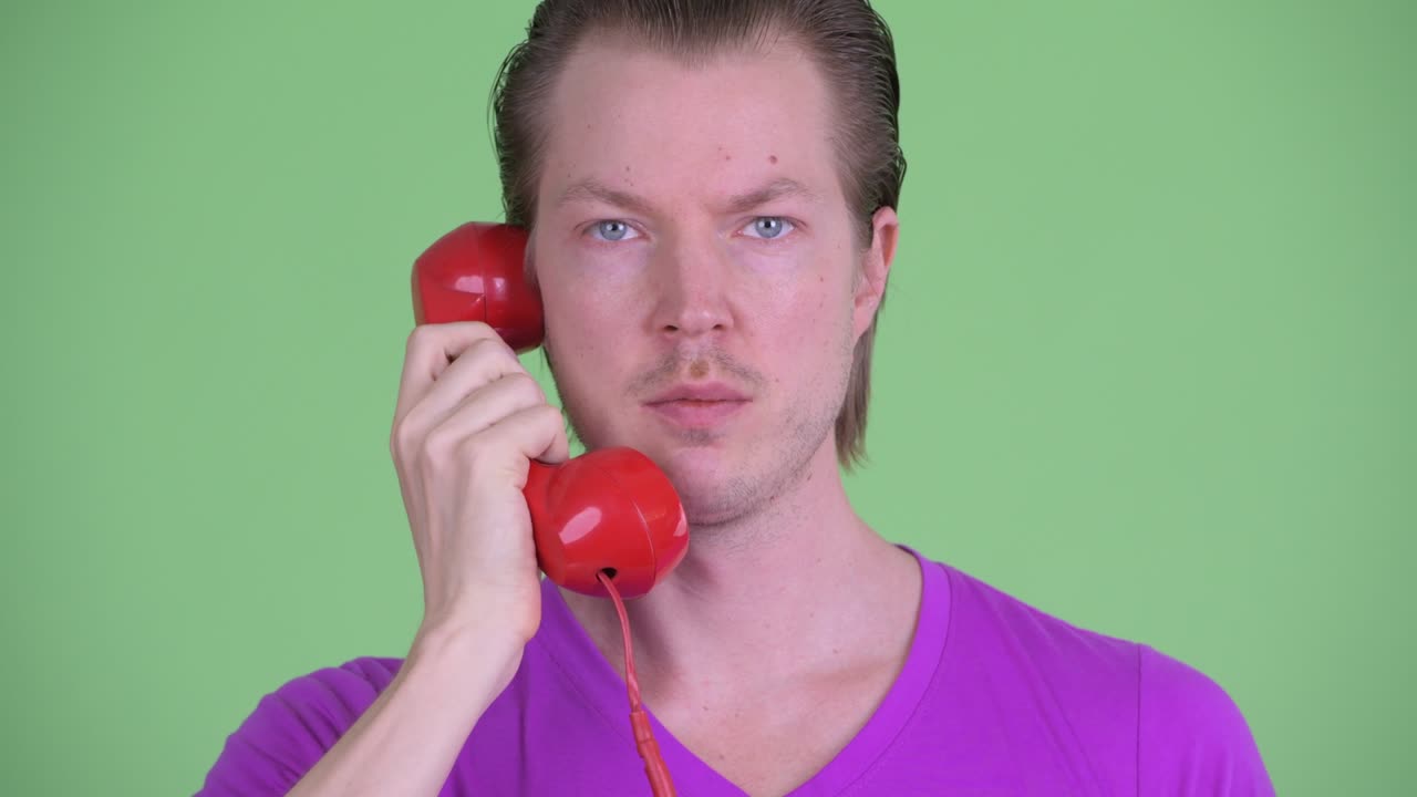 녹색 배경 에 은 빨간 전화 에 응답 하는 젊은 남자 의  을 확대