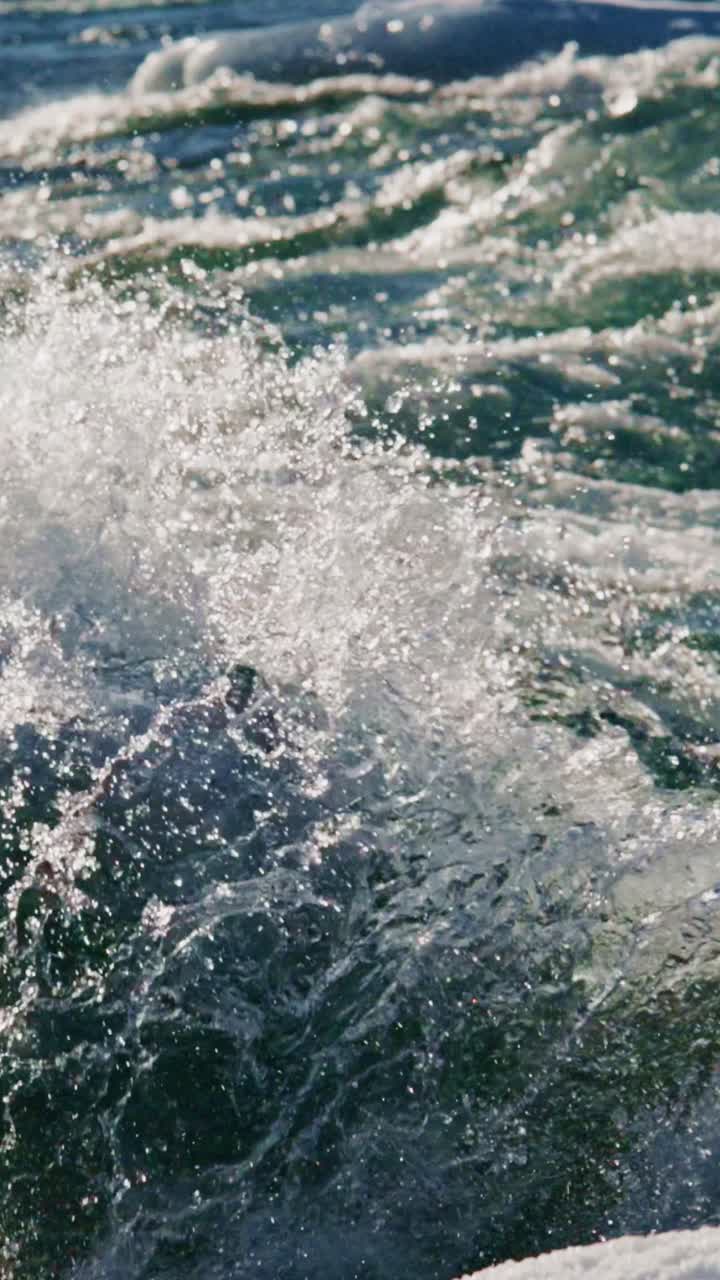 Onde che si infrangono contro la riva al tramonto con acqua scintillante in una località costiera.