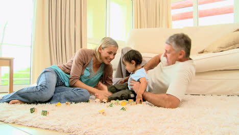 padres jugando con el bebé en la alfombra de la sala de estar