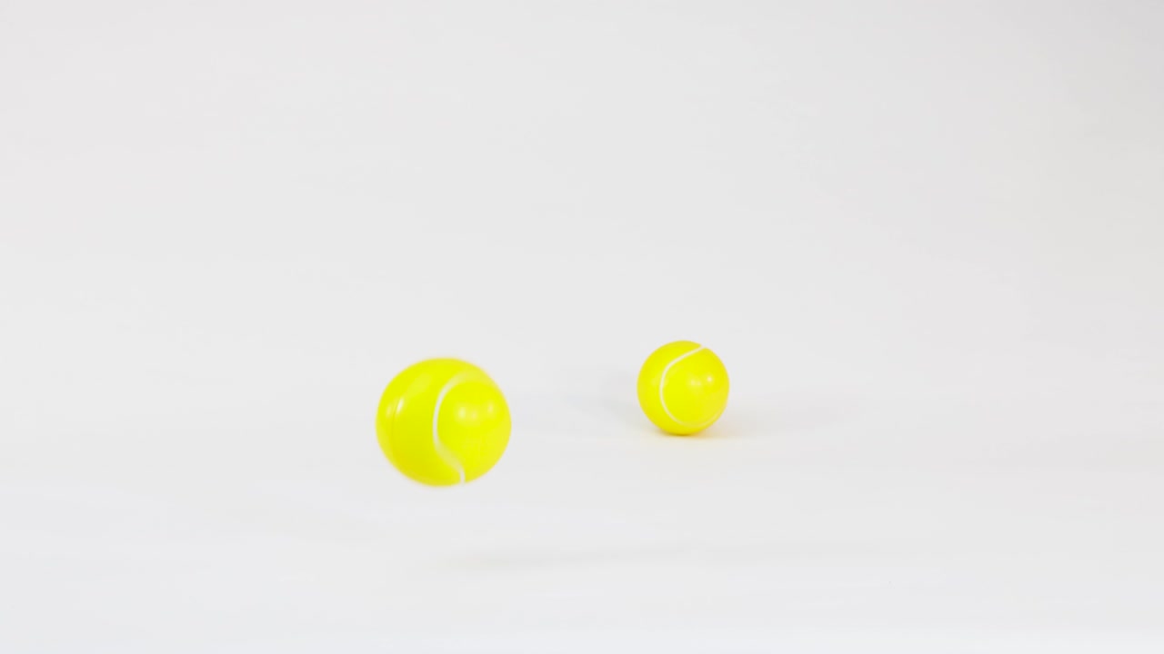 Multiple yellow tennis balls bounce and roll across a clean white studio background