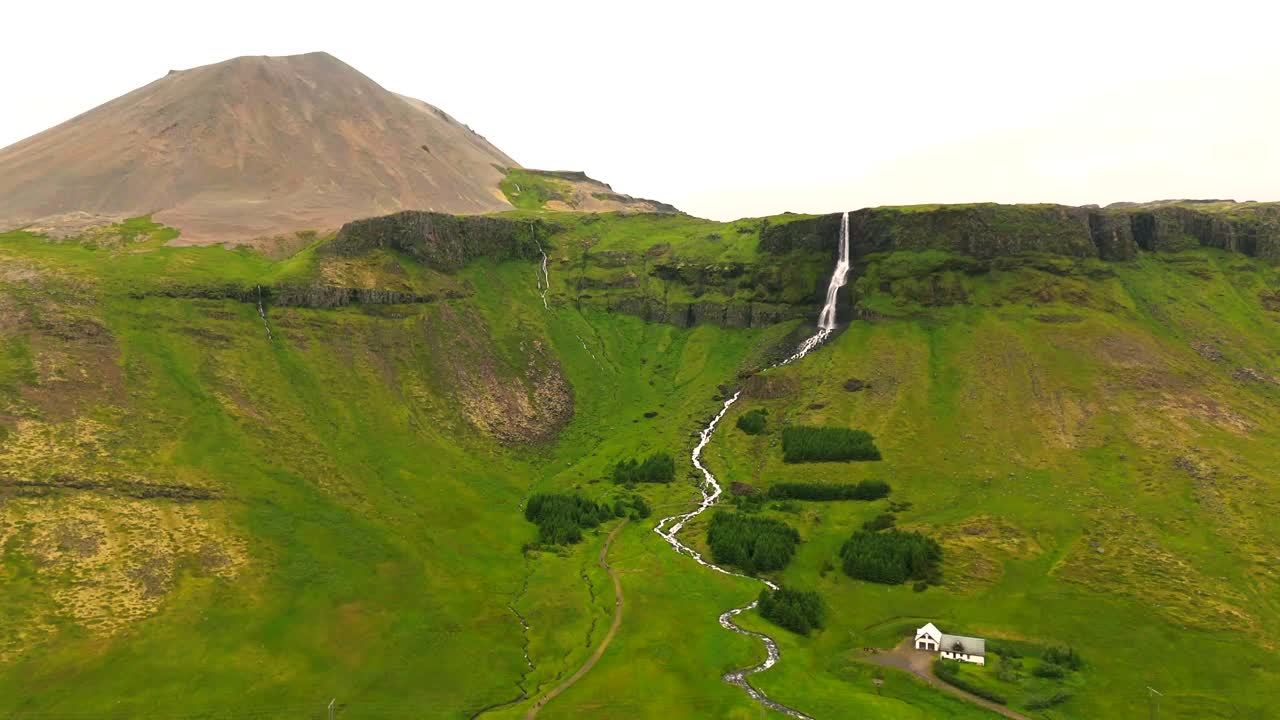 bjarnarfoss 위로 날아가, 폭포가 극적으로 거친 절벽 아래로 떨어지는 곳, 아이슬란드의 원시 야생의 놀라운 풍경에 둘러싸여 있습니다.
