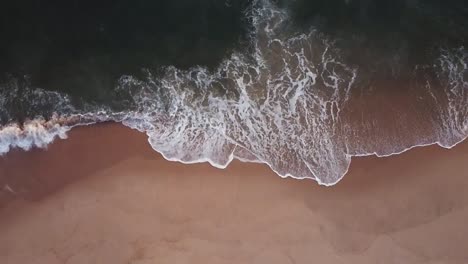 Drone-Shot-Top-View-Waves-hitting-the-sand