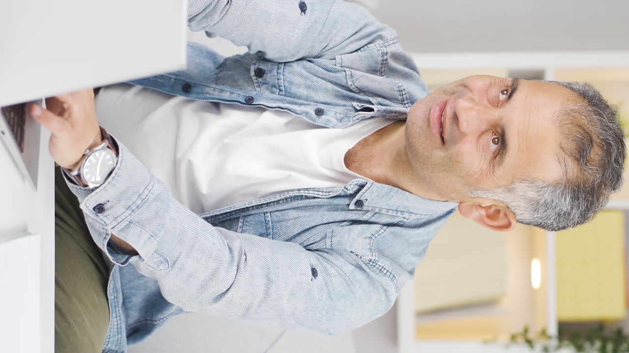 video vertical de expresión negativa de un hombre usando una computadora portátil.