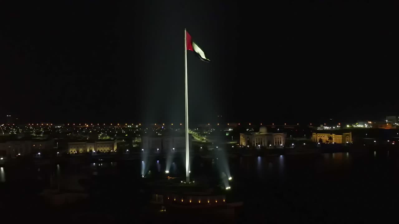 4K: Aerial night view of the Flag of the United Arab Emirates waving in the air, The national symbol of the United Arab Emirates