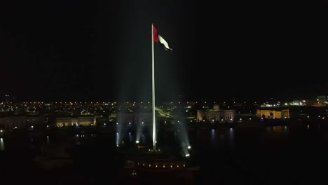 4k:-Vista-Aérea-Nocturna-De-La-Bandera-De-Los-Emiratos-árabes-Unidos-Ondeando-En-El-Aire,-El-Símbolo-Nacional-De-Los-Emiratos-árabes-Unidos