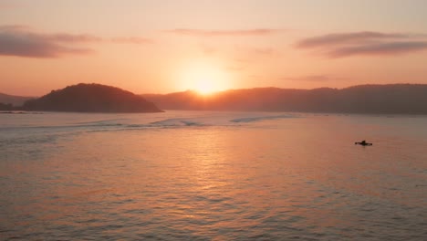 Sunrise-at-the-surf-spots-of-Gerupuk-in-Lombok,-with-a-view-on-the-bay-with-the-fishing-boats-and-surfers