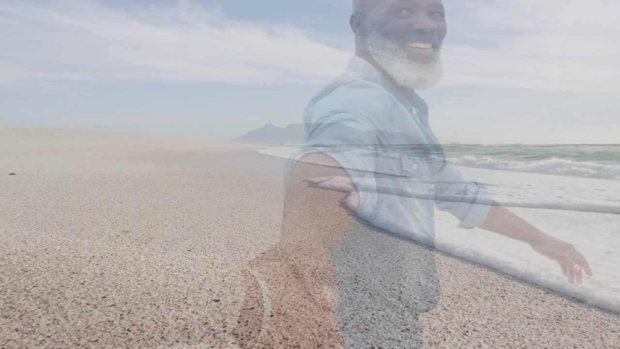 Uomo che cammina su una spiaggia di ciottoli, con la fotocamera in mano, guardando indietro e sorridendo, con un'immagine dell'oceano in sovrapposizione a fini di marketing.