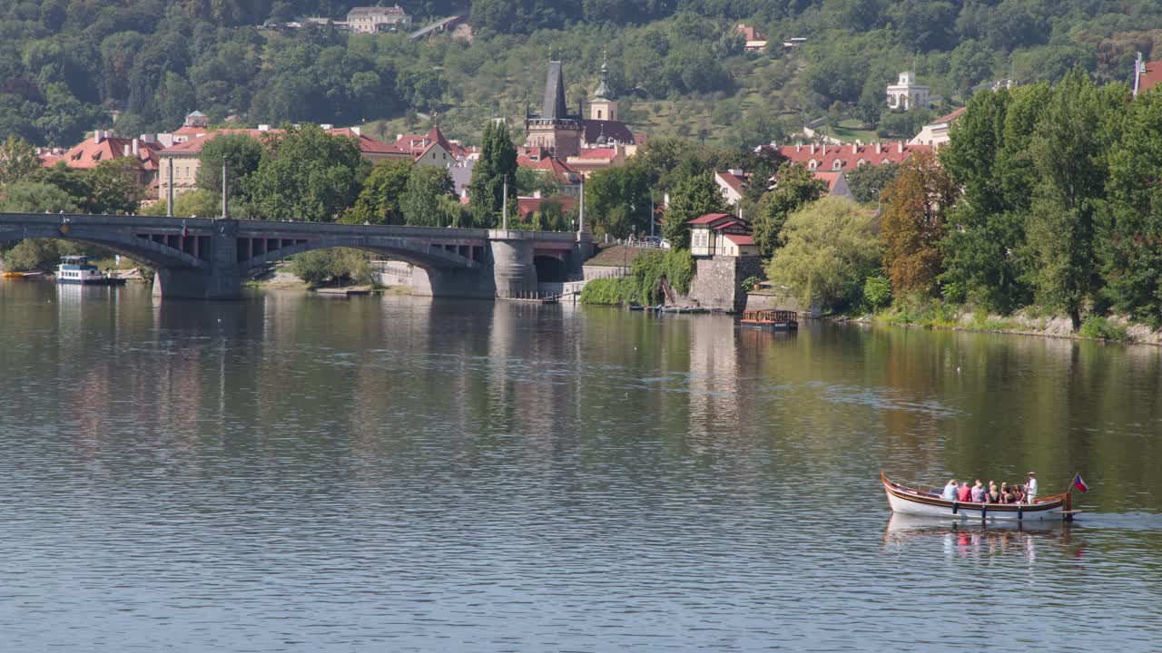 Barca a remi con turisti che attraversa il tranquillo fiume Moldava, Praga, sotto la luce del giorno, sfondo panoramico