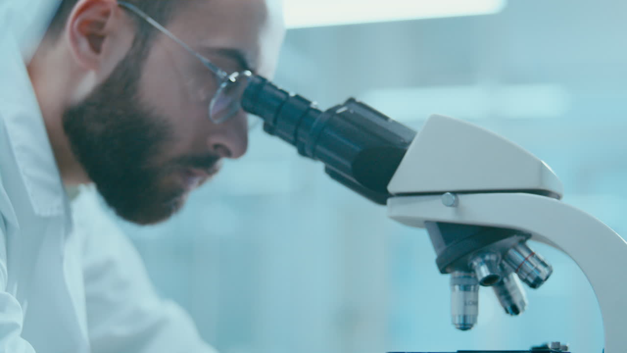 Lab Scientist Adjusting Microscope Focus Knob during Sample Examination