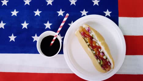 Hot-Dog-Servido-En-Plato-Con-Una-Bebida-En-La-Bandera-Americana