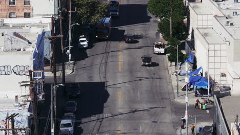 high-angle view of a city street with traffic, buildings, and a roadside encampment