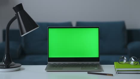 notebook with green screen for chroma key technology, zooming shot on table in living room, remote working place in home