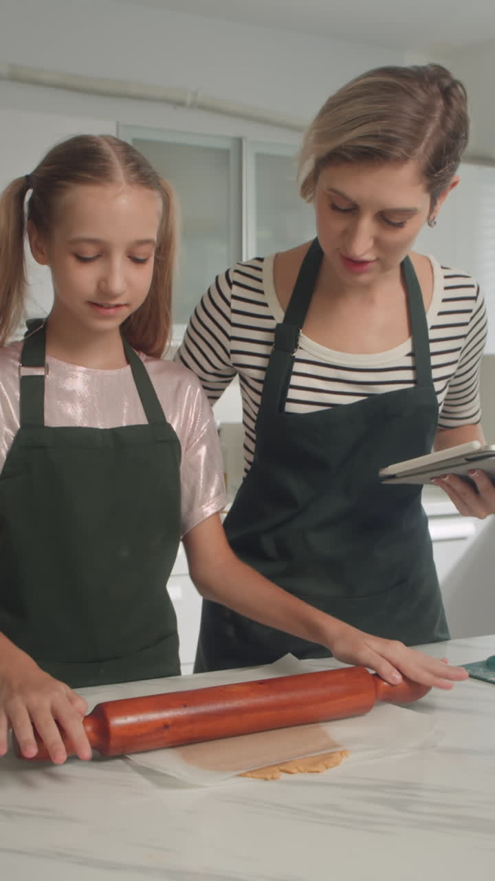 Mother Helping Daughter Rolling Dough at Kitchen