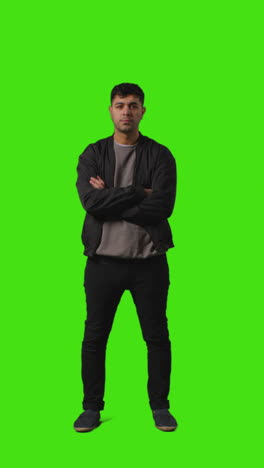 vertical video full length portrait shot of bored or fed up looking man standing against green screen