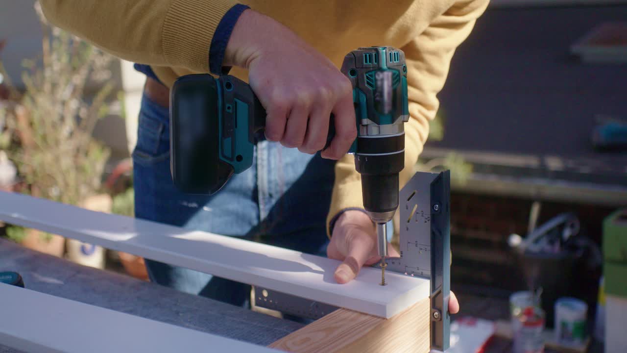 мастер вкручивает шуруп в дерево