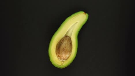 aguacate maduro y cortado orgánicamente girando rápidamente sobre un fondo negro.