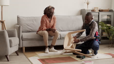 Carpenter Helping African-American Woman Assembling Chair