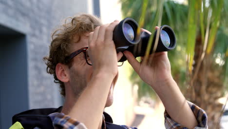 young hipster is looking on binoculars and smiling