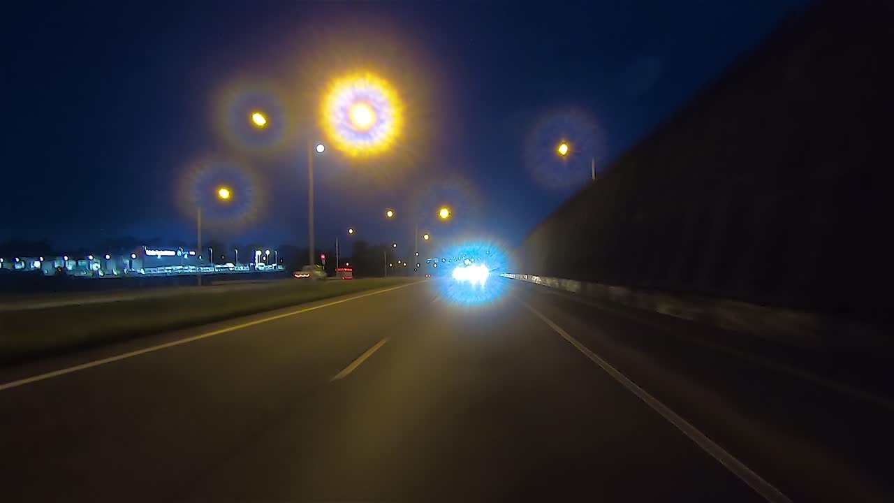 punto de vista de conducción nocturna mirando hacia atrás para el reemplazo de la pantalla verde de la escena interior del automóvil: conducir a lo largo de una concurrida autopista o autopista suburbana, pasando por debajo de puentes